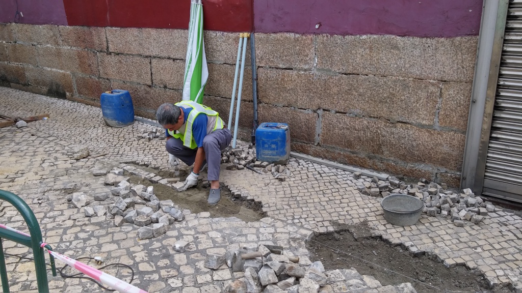 Worker is paving the cobblestone street floor next to A-Ma Temple of Macau