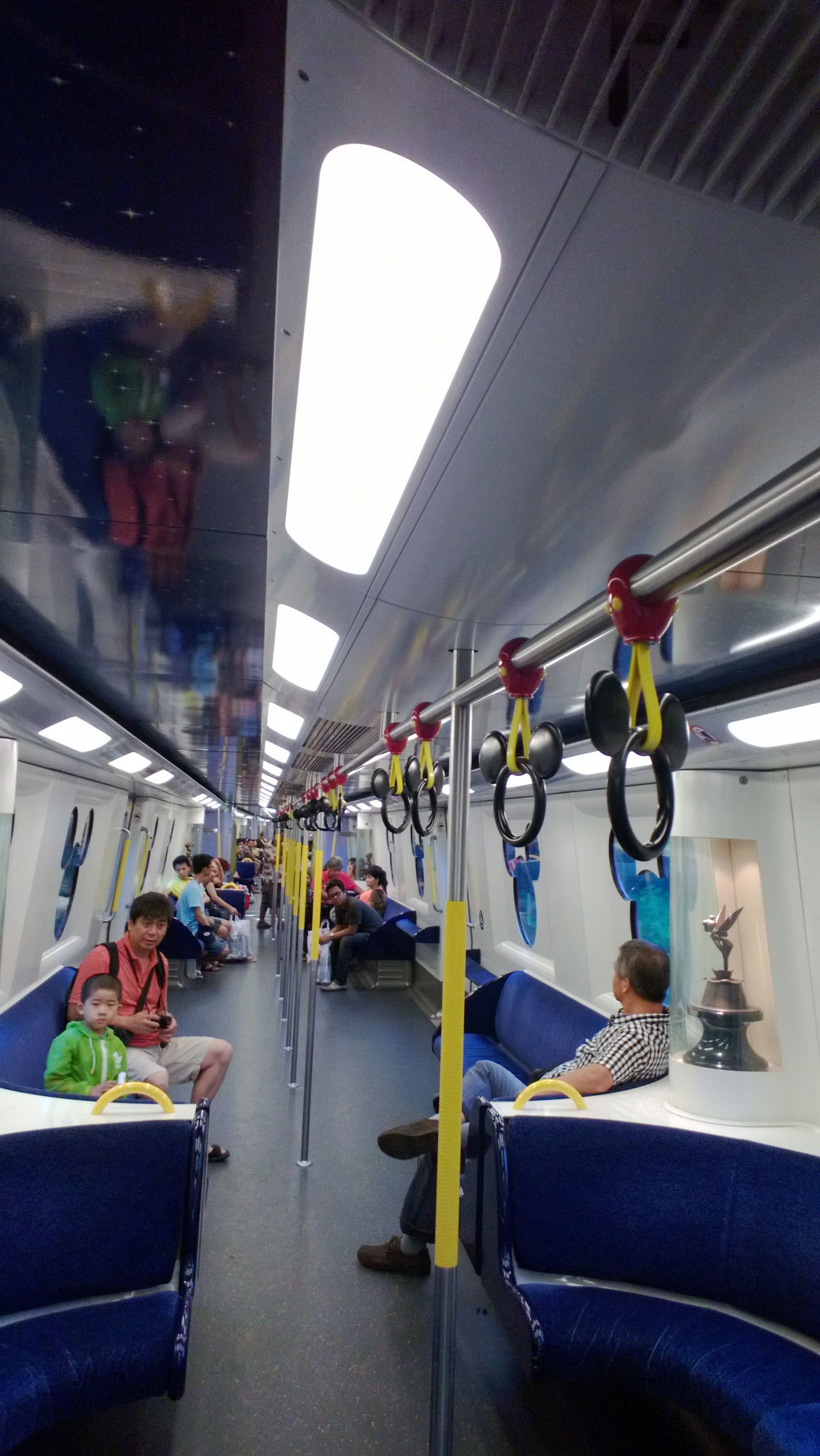 Disneyland Resort Line train compartment, blue sofa, passengers Mickey Mouse handrails.