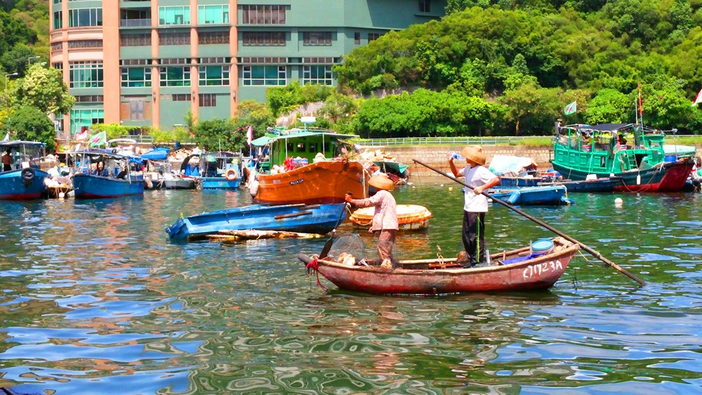 Common fishermen are fishing at the Aberdeen Fishing Village by their small boat