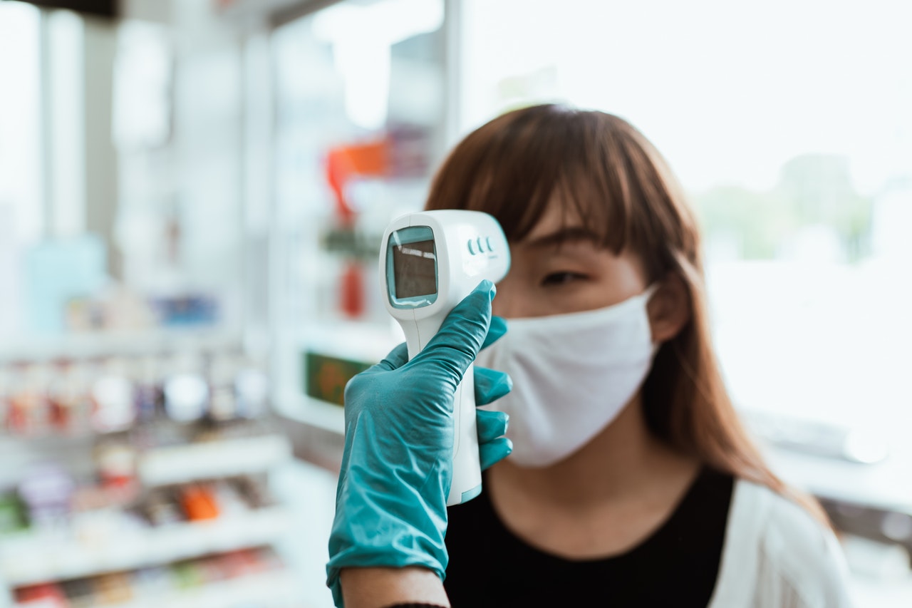 checking temperature, woman with blonde hair wearing mask