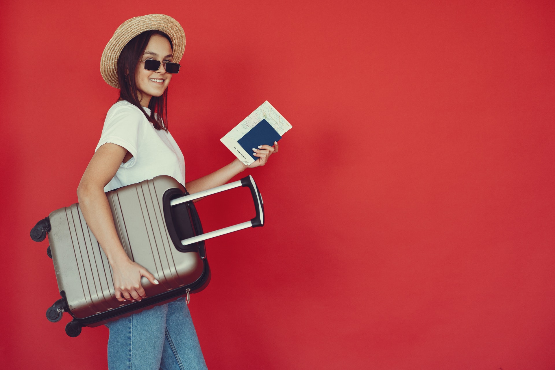 happy-female-traveler-with-suitcase-on-red-background