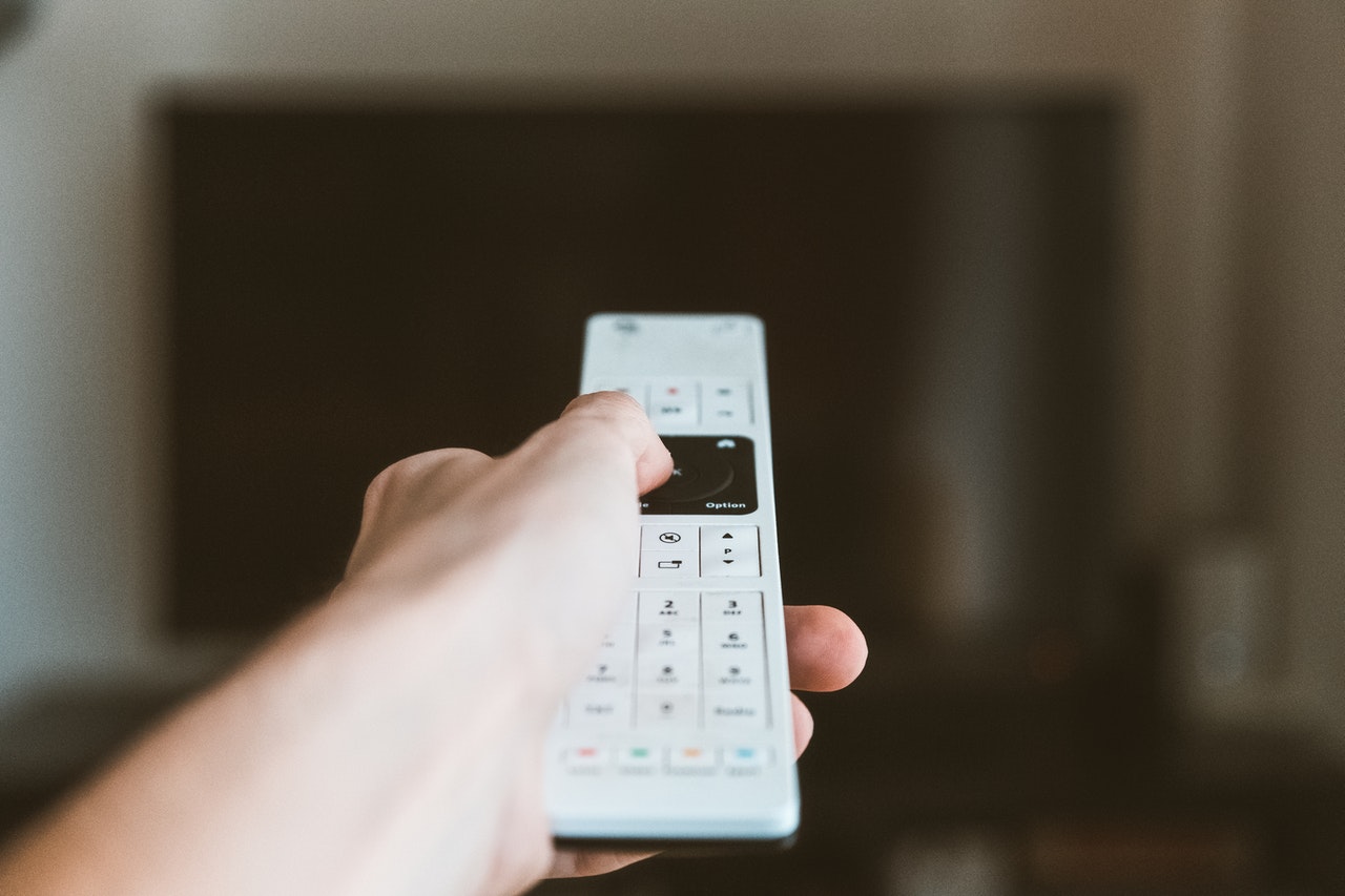 Hand holding White TV remote controller