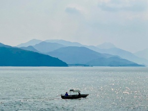 misty sky, hills, sea, boat, anglers