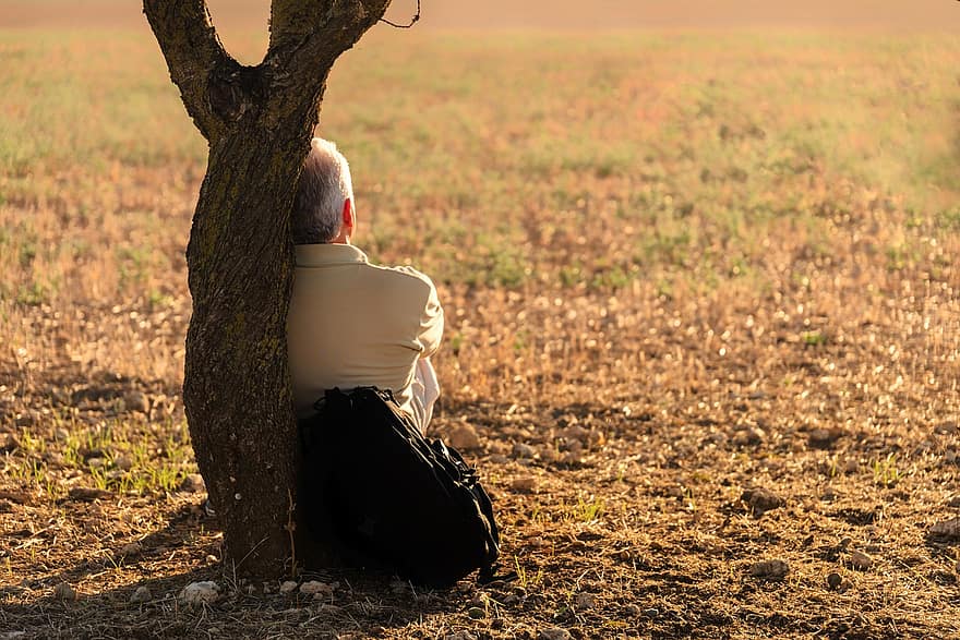 A man leans against to a tree to take a rest