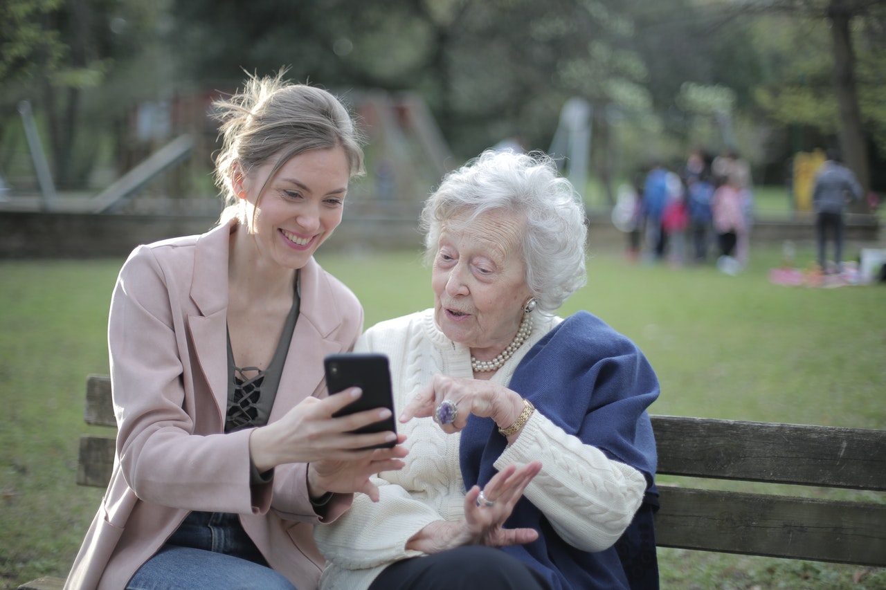 daughter and mother in park looking at phone